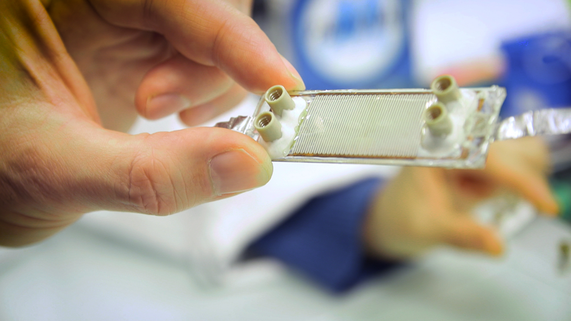 Gros plan d'une main qui tient un petit réseau microfluidique pour des réactions chimiques